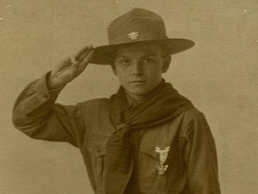Photograph of a boy scout in uniform saluting.