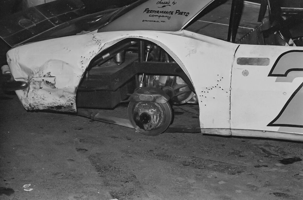 A close-up of the damaged right rear wheel well of Larry Phillips' race car after the 1976 Missouri State Asphalt Championship. The tire is completely gone and there is substantial damage to the rear of the car.