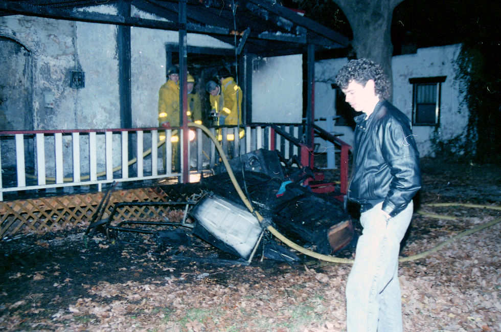 Brad Evans stands outside of the burned exterior of his home as firefighters work inside.