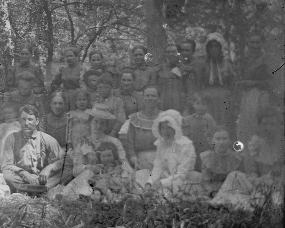 Black and white group portrait of members of the Turner family and associates. A woman sitting in the front is wearing what might be described as a white zephyr on her head and shoulders.