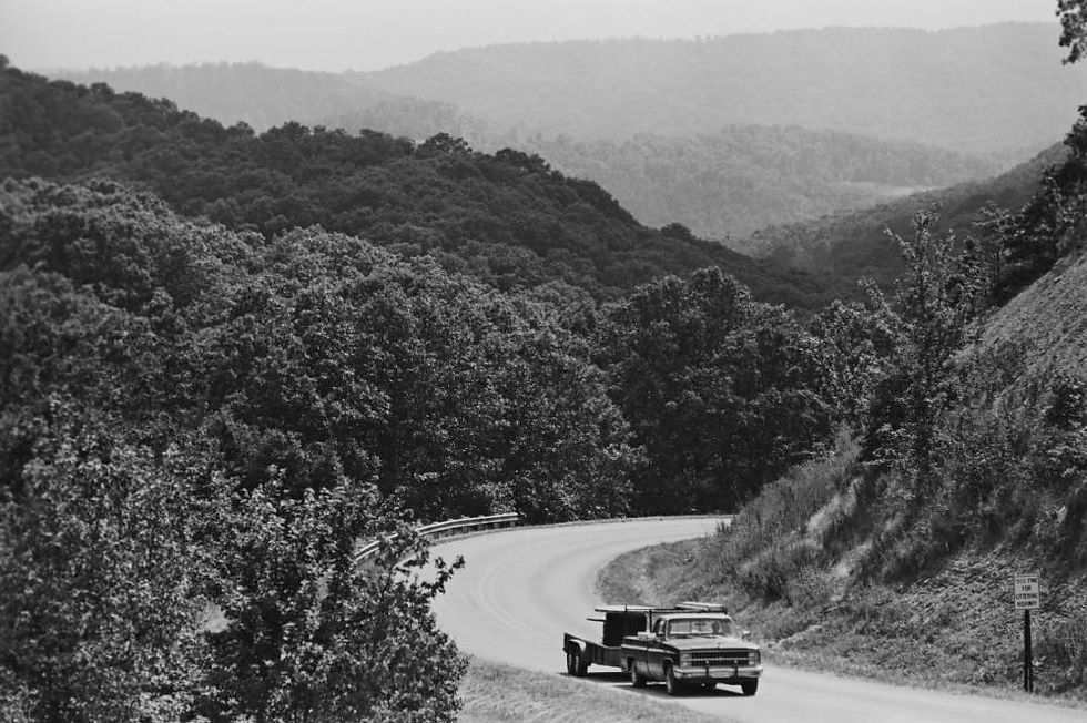 A pickup truck drives along a winding road in the Boston Mountains of Arkansas.