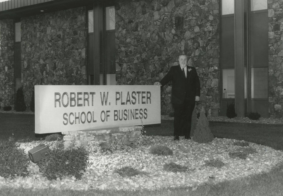 Robert W. Plaster poses next to the Robert W. Plaster School of Business Building at College of the Ozarks.