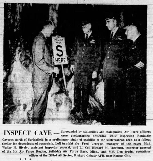 A newspaper clipping featuring a black and white photo of officials in Fantastic Caverns standing in front of stalactites and stalagmites. Fred Veregge, Fantastic Caverns manager, holds a sign reading "Shelter Area S Here." Caption text reads:

Inspect Cave -- Surrounded by stalagtites and stalagmites, Air Force officers were photographed yesterday while inspecting Fantastic Caverns north of Springfield in a preliminary study of usability of the subterranean area as a fallout shelter for dependents of reservists. Left to right are Fred Veregge, manager of the cave; Maj. Walter H. Hively, assistant inspector general, and Lt. Col. Richard M. Thorburn, inspector general of the 5th Air Force Region, Selfridge Air Force Base, Mich., and Maj. Don Irwin, operations officer of the 2483rd AF Sector, Richard-Gebuar AFB, near Kansas City.
