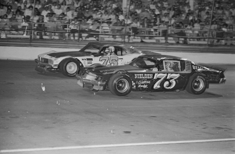 Drivers Dave Watson and Larry Phillips pass by the grandstand in their race cars during the pace lap of the 1976 Missouri State Asphalt Championship.
