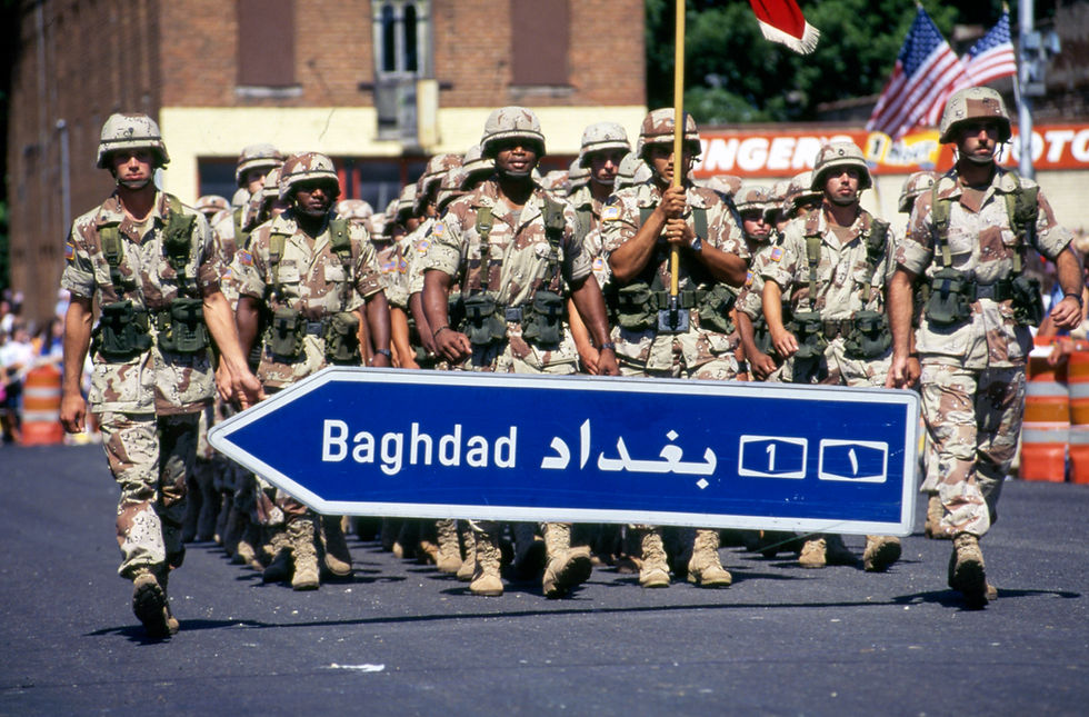 Veterans in military uniforms march at the 1991 Fourth of July parade in Marshfield. Text on sign reads "Baghdad" in Latin alphabet and Arabic script.
