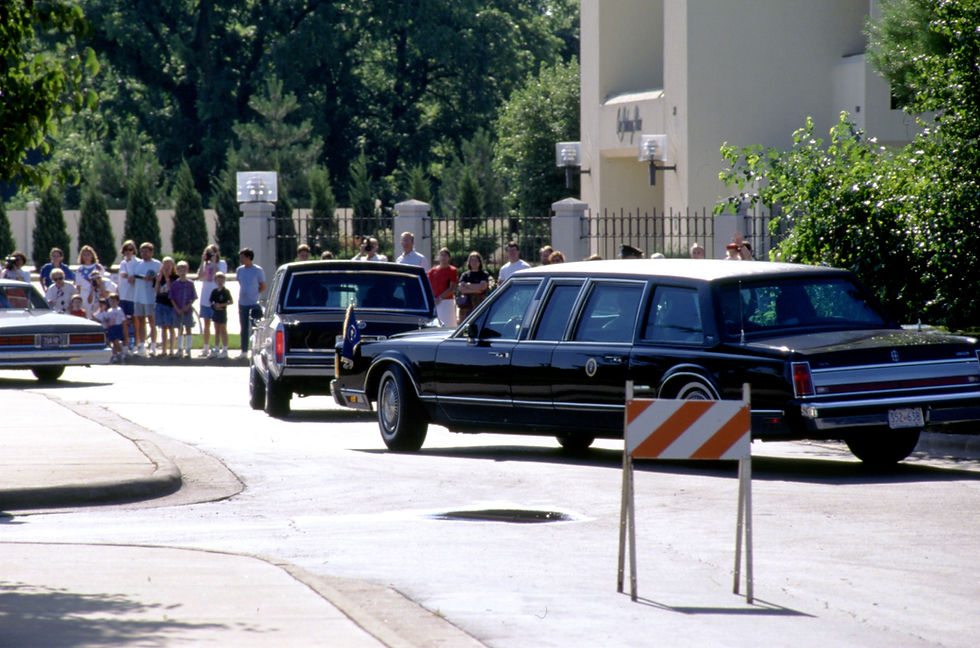 President George H. W. Bush's motorcade departs from University Plaza Hotel on July 4, 1991. Dozens of onlookers watch as the motorcade drives by.