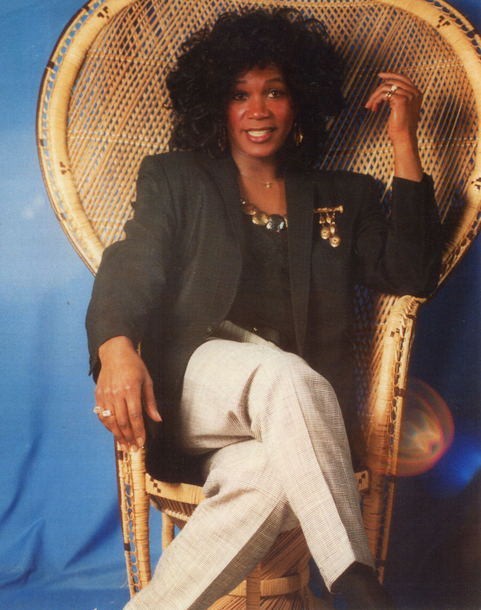 Dwayne Pike, dressed in his drag persona, the Tigress, sits in a chair for a portrait.