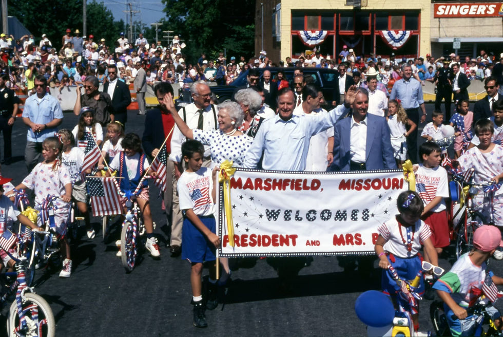 President George H. W. Bush and First Lady Barbara Bush lead Marshfield's 1991 Fourth of July Parade. Text on sign reads: "Marshfield, Missouri Welcomes President and Mrs. Bush."
