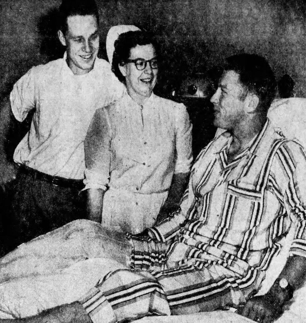 A newsprint photograph of Bill Virdon and Nurse Corinne Andrews standing at the beside of Mickey Mantle at Burge Hospital. Mantle is wearing pajamas.