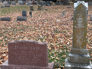 The gravestones of Davis and Lewis Tutt at Maple Park Cemetery. Davis's headstone is newer and constructed of polished granite. Text on Davis's headstone reads: "Davis Tutt. Born 1839 In Yellville Arkansas. Died July 21, 1865 on the public square in Springfield, Missouri." Lewis's monument, an obelisk, is covered in lichen. Text on Lewis's gravestone reads: "Lewis Tutt. Nov 1 1827. Jan. 13. 1900."