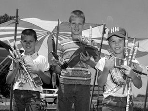 A black and white photograph of three young boys holding fireworks.