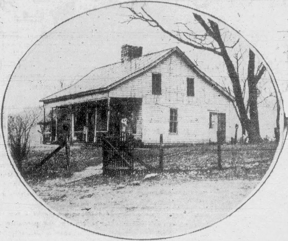 A black and white photograph of the home of W. B. Cox and Mrs. Cox in Oto, Missouri. The photograph is encircled and framed with a thin black line. The home has two stories, wide gables, and a front porch. A tall, bare tree stands next to the house. 