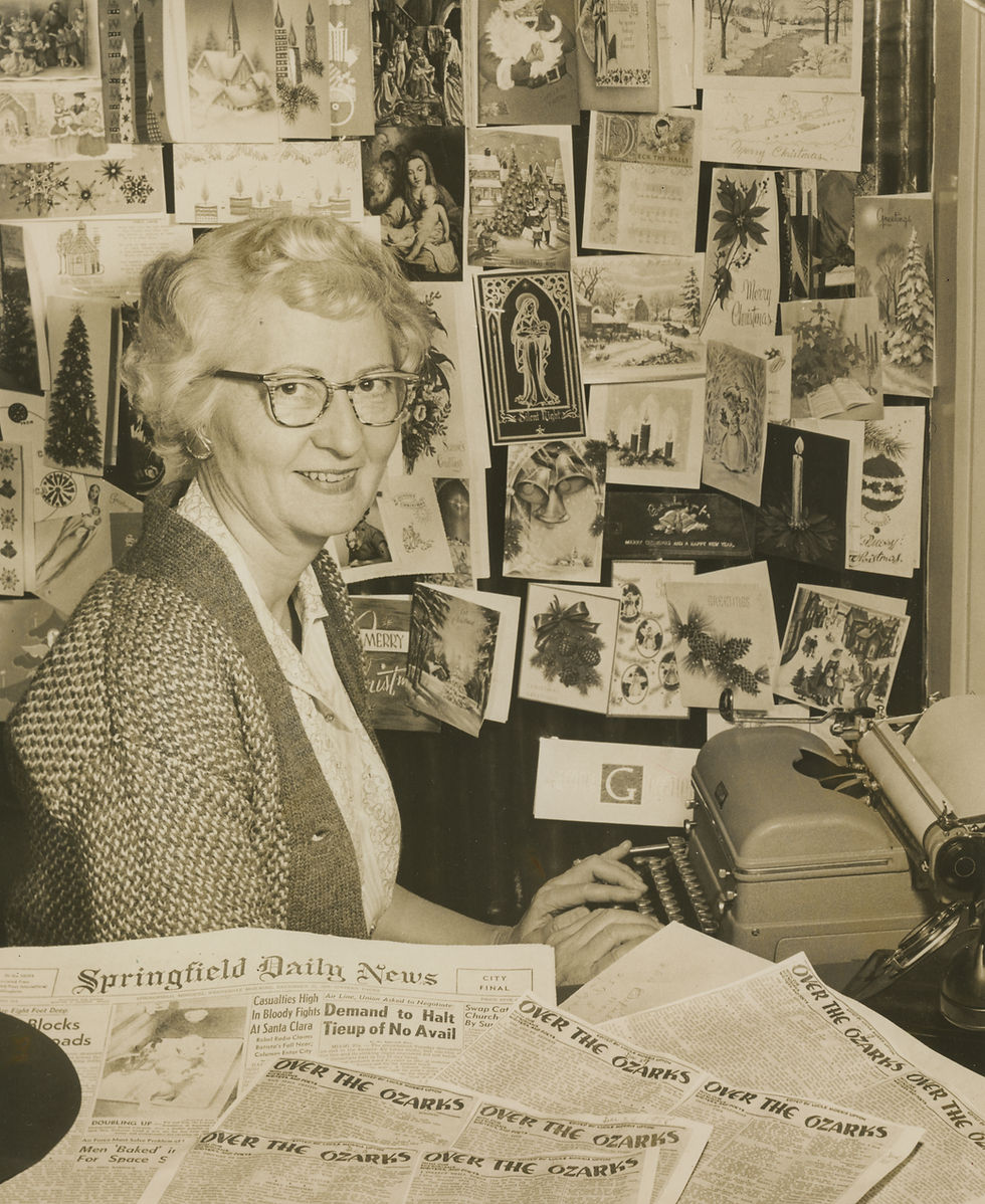 Lucile Morris Upton sitting at her typewriter with newspapers on her desk.