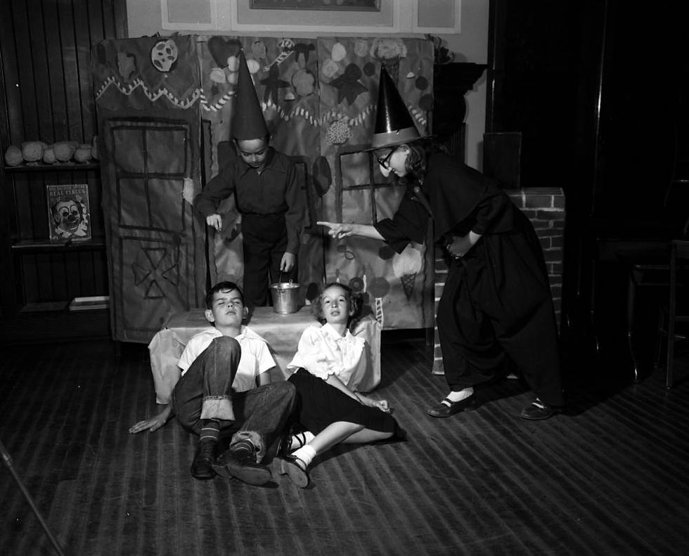 A black and white photograph of a York Elementary students acting in a Hansel and Gretel operetta. The Witch and the Sandman loom over the recumbent Hansel and Gretel.