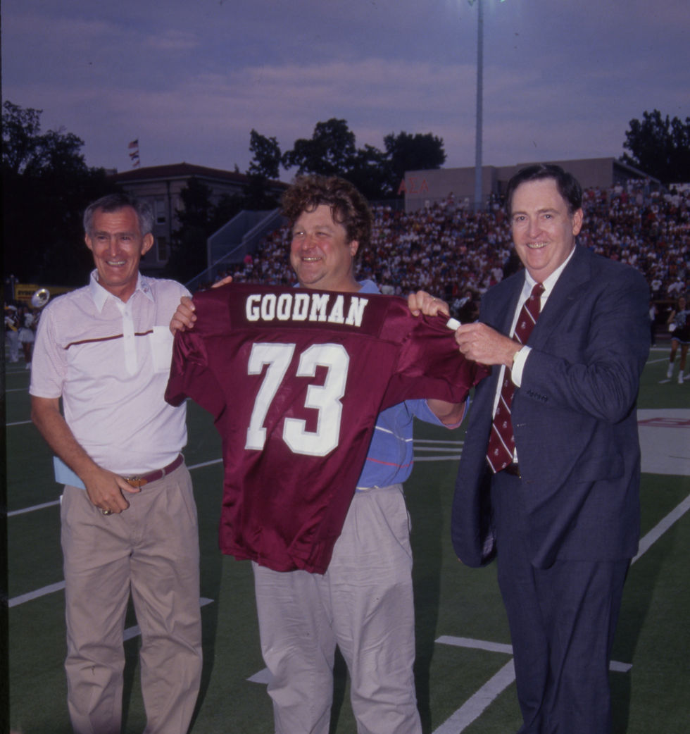 John Goodman holds up the SMS football jersey bearing his name at Plaster Stadium.