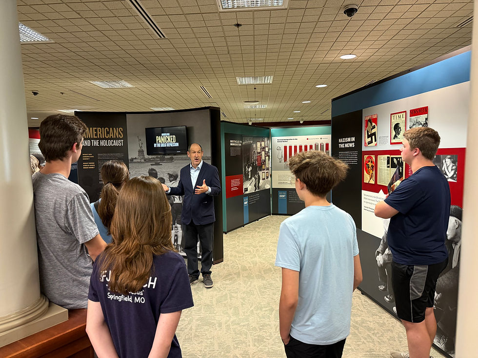 Historian and curator of the Americans and the Holocaust traveling exhibit, Daniel Greene, gives a tour of the exhibit to teenage patrons at the Library Center.