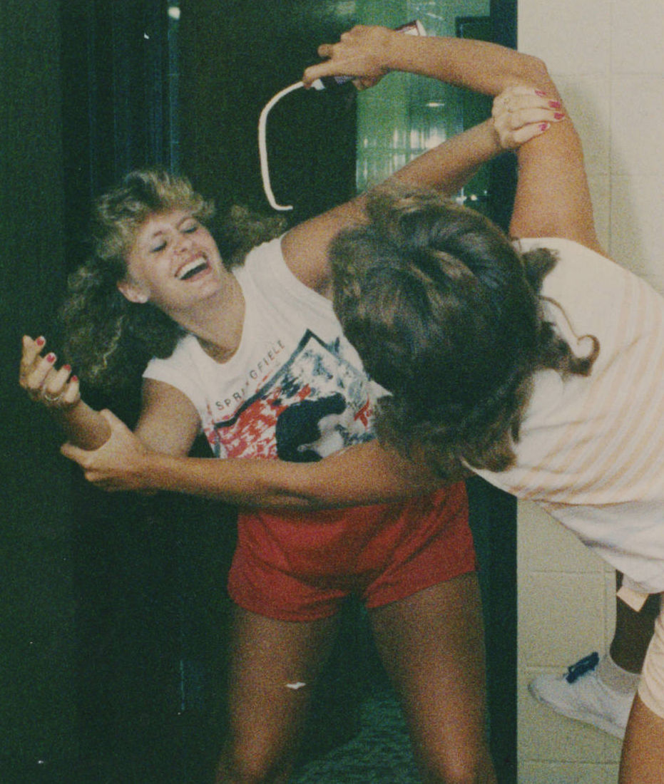 A photograph of Marionville High School cheerleaders Michelle Harris and Mitzi Nelson play-fighting one another. Mitzi is spraying shaving cream at Michelle.