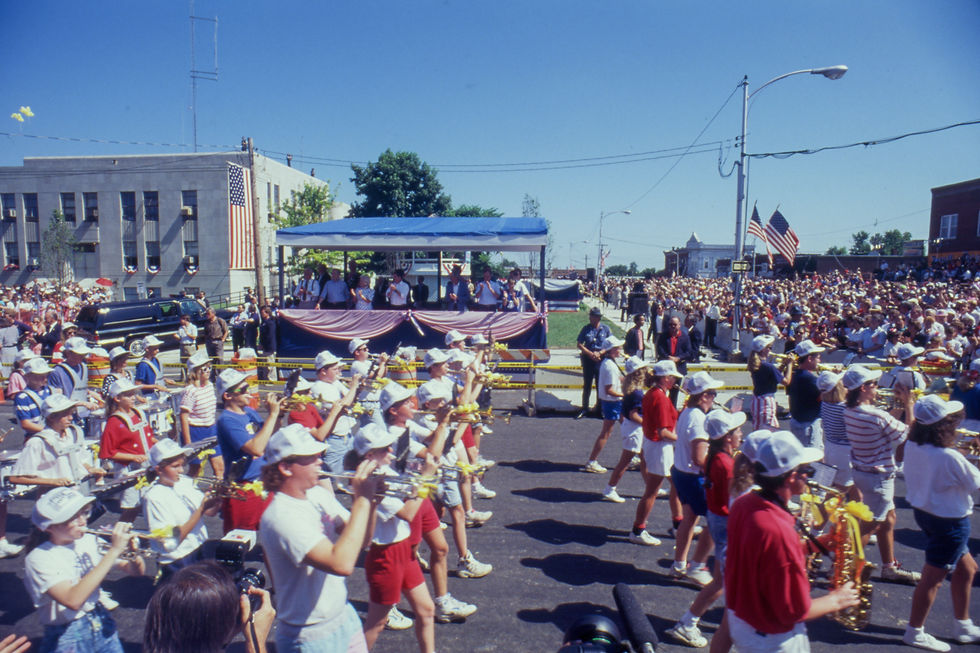 Musicians march past a review stand in which George H. W. Bush and other dignitaries watch the 1991 Fourth of July parade in Marshfield.