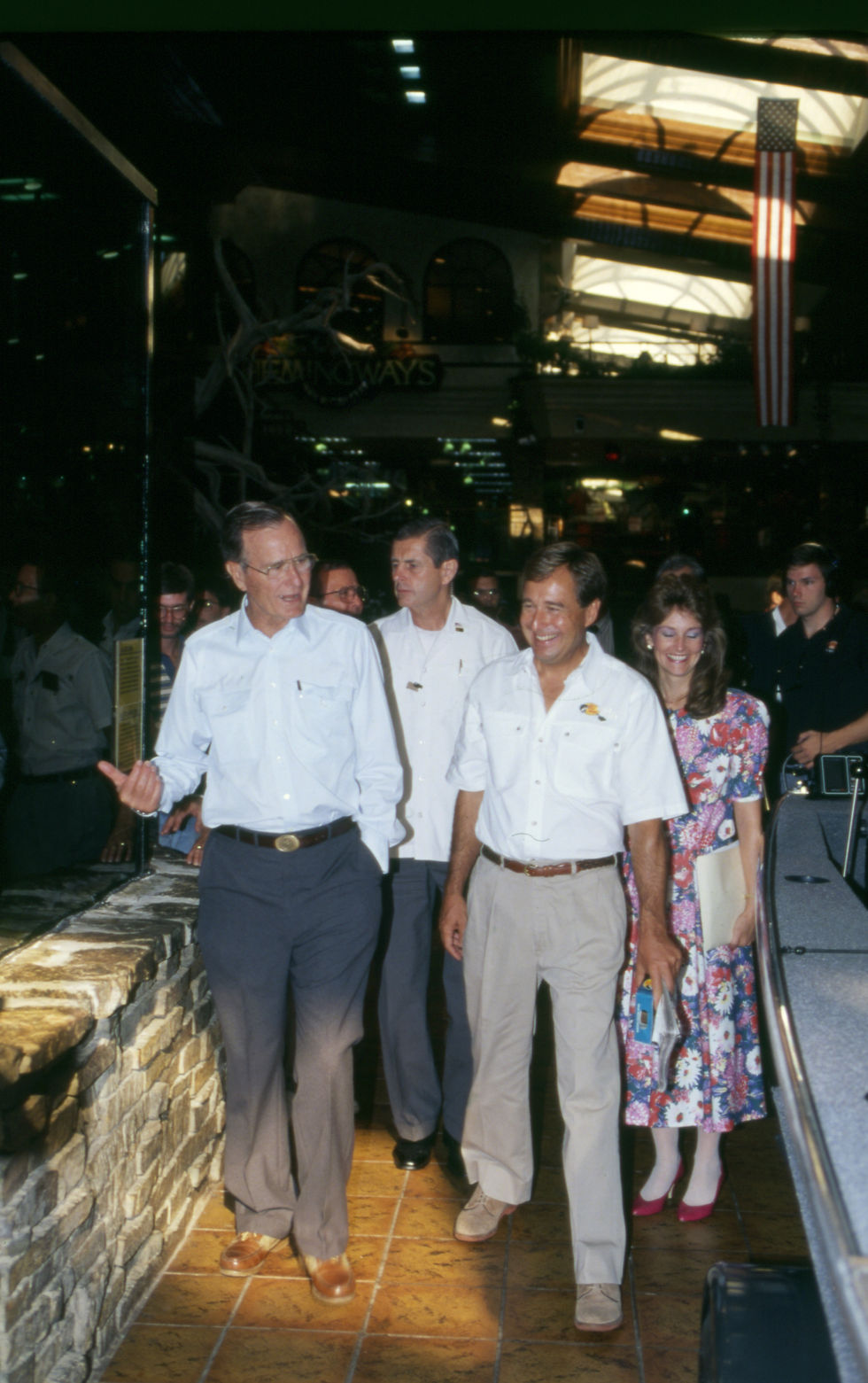 President George H. W. Bush, Johnny Morris, and a large group of unidentified people walk through the Bass Pro Shops Outdoor World in Springfield, Missouri.