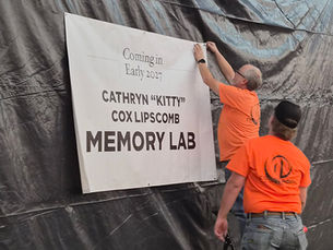 Workers put up a sign that reads "Coming in Early 2027: Cathryn 'Kitty' Cox Lipscomb Memory Lab."