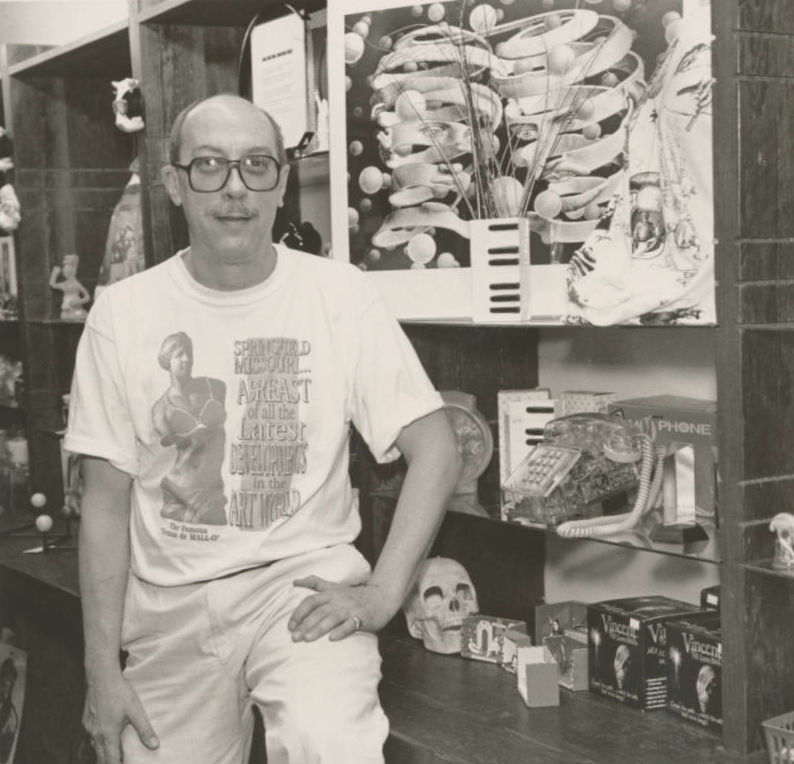A black and white portrait of Jim House. Jim is bald and is wearing a t-shirt and glasses.