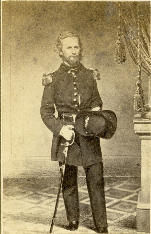 A full length photographic portrait of Union Brigadier General Nathaniel Lyon. Lyon is in uniform and is holding a saber in his right hand. He is a white man with middle-length, curly hair and a beard.