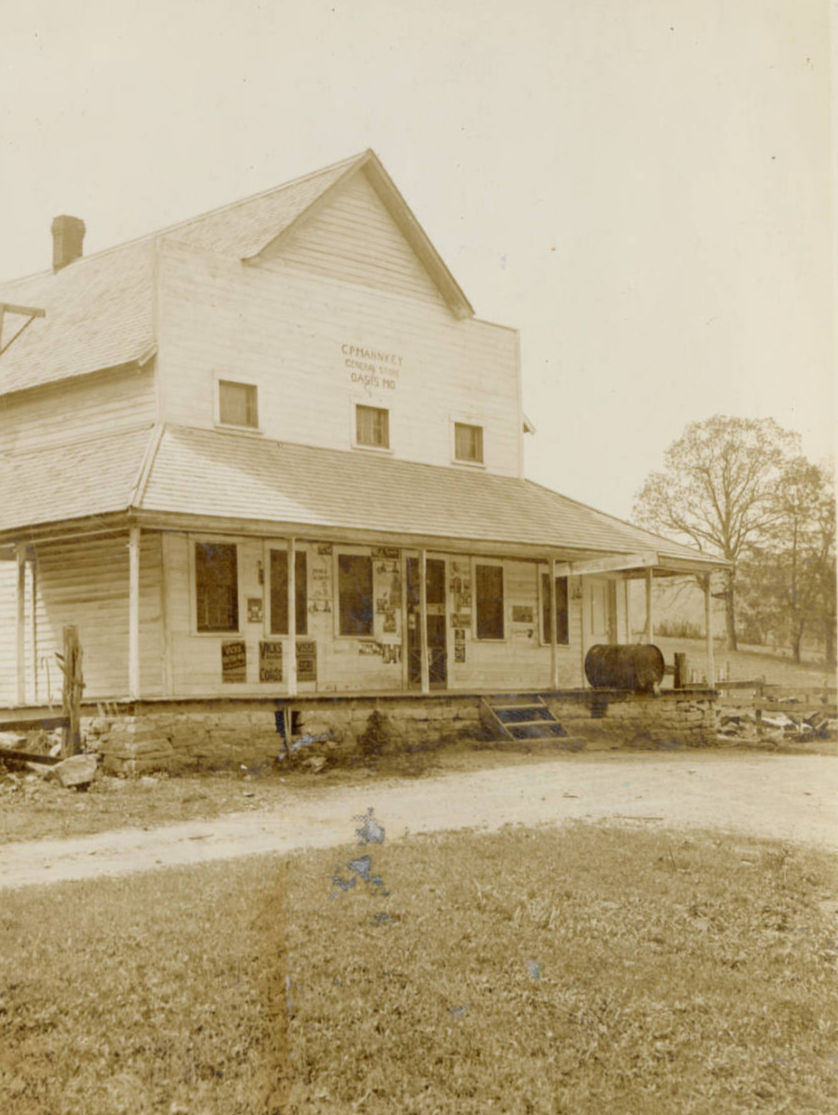 A sepia tone photograph of the C. P. Mahnkey General Store in Oasis, Missouri--a two story building with a front porch.