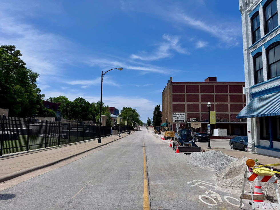 A street with construction, founders park is on the left, and the national audio company building is on the right