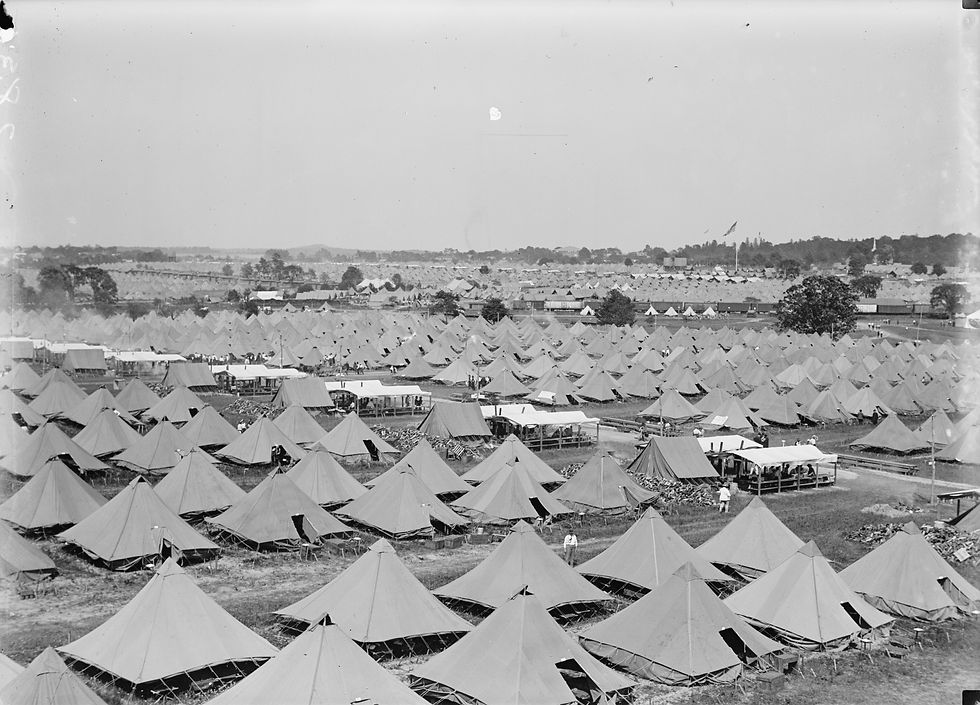 A black and white photo shows a vast field filled with hundreds of triangle tents