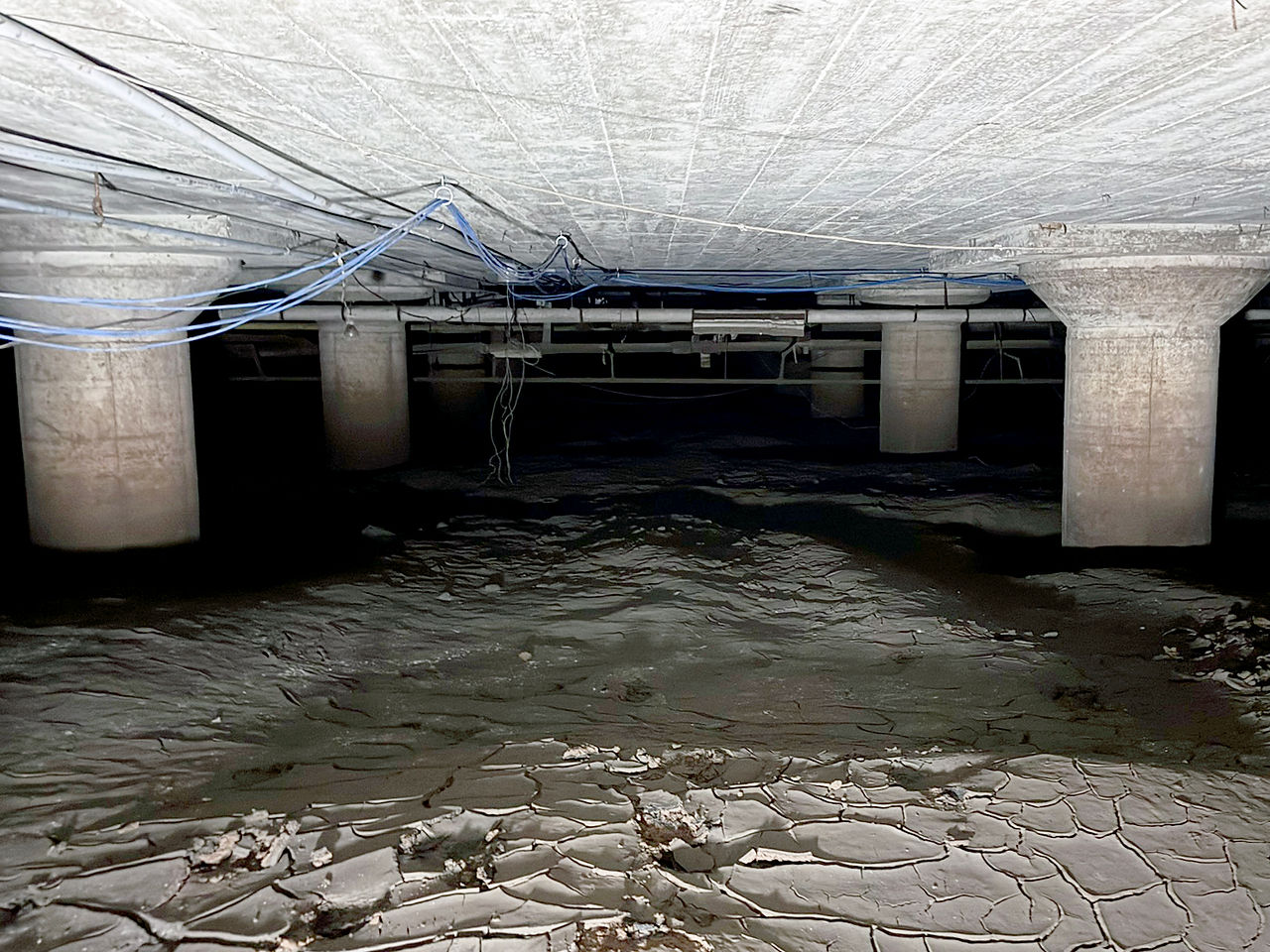 Concrete support beams are sunk into deep mud, leaving only a small amount of space between the mud and the ceiling