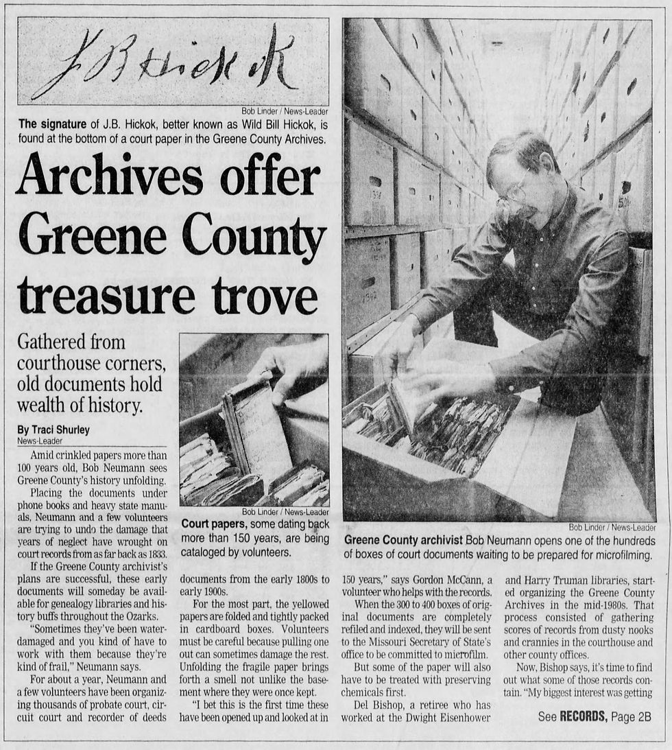 A newspaper clipping with the headline "Archives offer Greene County treasure trove". A photo of Hickok's signature is on top along with a photo of a man with glasses looking through a box of files and a close-up photo of old files being lifted out of a box. 